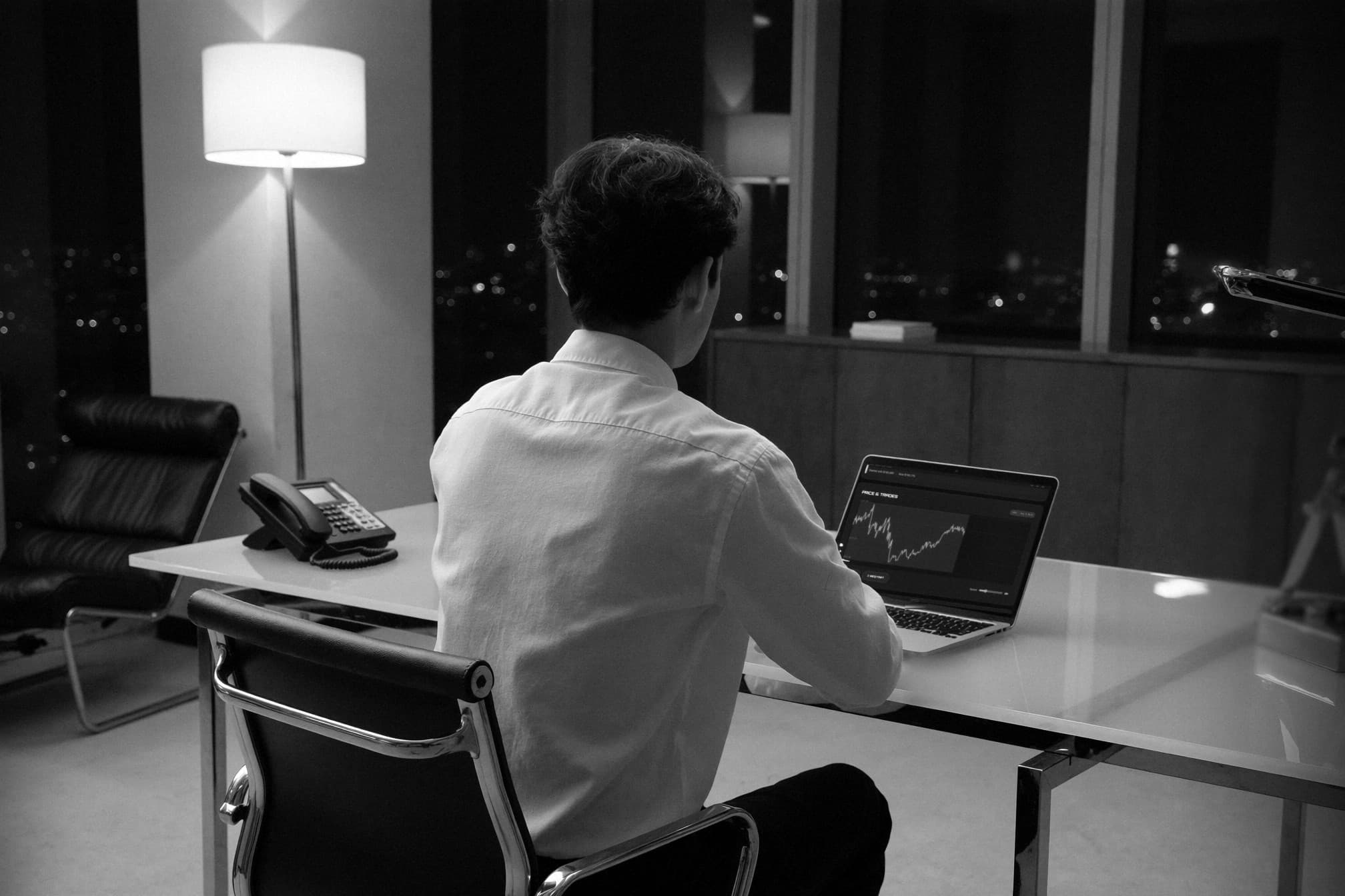 Bruce Destrier Specter at the desk at night, a trading dashboard open on a laptop